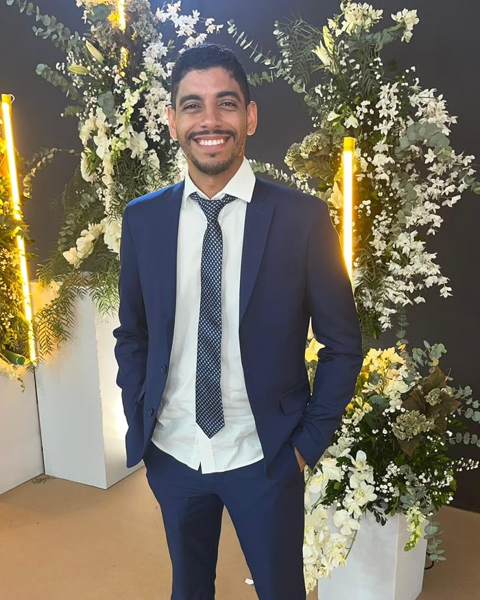 Victor Hugo Sales Santos, de terno azul, sorrindo em um evento organizacional